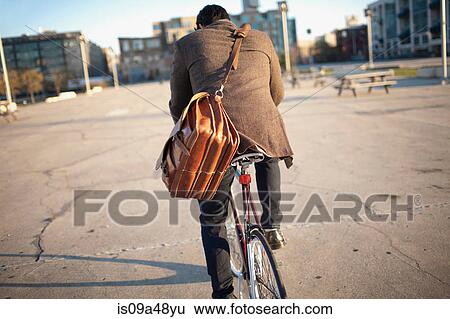 Stock Photograph - Man riding bicycle on city street. Fotosearch