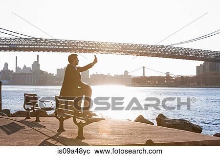 Stock Image - Man taking pictures of urban bridge. Fotosearch