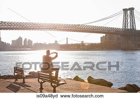 Stock Image - Man taking pictures of urban bridge. Fotosearch