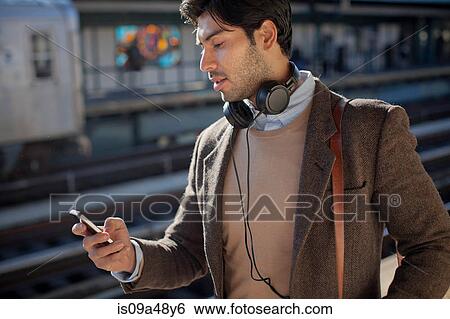 Man using cell phone at train station View Large Photo Image Stock Photograph - Man using cell phone at train station. Fotosearch