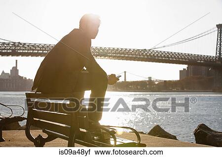 Stock Image - Man using cell phone by urban bridge. Fotosearch