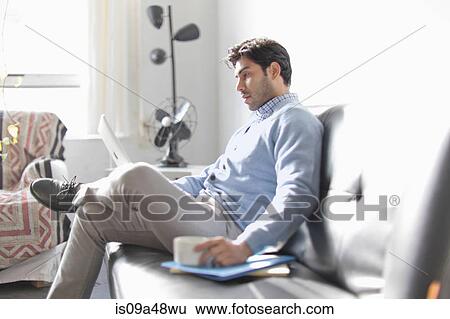 Man using laptop on sofa View Large Photo Image Stock Photograph - Man using laptop on sofa. Fotosearch