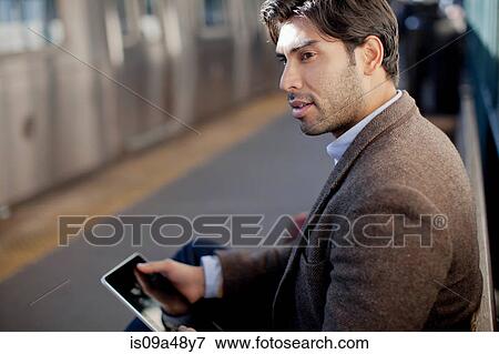 Stock Photo - Man using tablet computer at station. Fotosearch