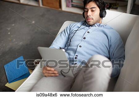 Man using tablet computer on sofa View Large Photo Image Stock Photograph - Man using tablet computer on sofa. Fotosearch