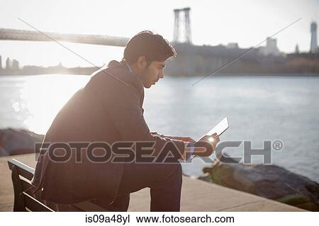 Stock Image - Man using tablet computer outdoors. Fotosearch
