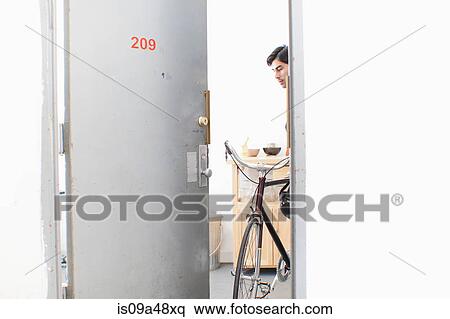 Man wheeling bicycle out apartment door View Large Photo Image Stock Photography - Man wheeling bicycle out apartment door. Fotosearch