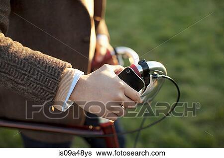 Man with cell phone pushing bicycle View Large Photo Image Stock Photograph - Man with cell phone pushing bicycle. Fotosearch