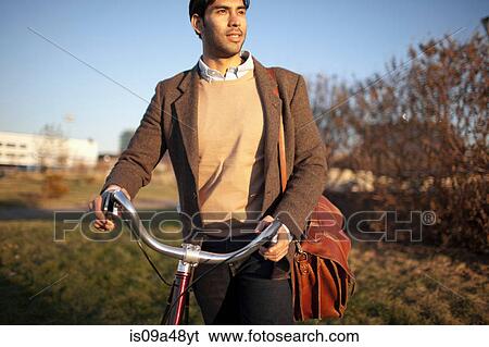 Man with cell phone pushing bicycle View Large Photo Image Stock Photograph - Man with cell phone pushing bicycle. Fotosearch