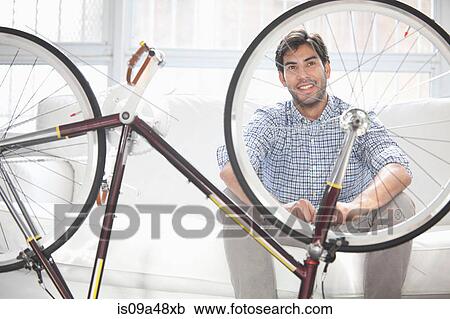 Man with upturned bicycle indoors View Large Photo Image Stock Image - Man with upturned bicycle indoors. Fotosearch
