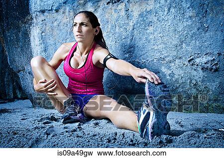 Stock Photo - Runner stretching in sand. Fotosearch