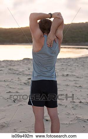 Picture - Runner stretching on beach. Fotosearch