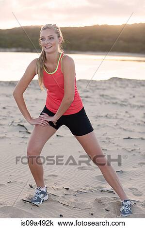 Stock Image - Runner stretching on beach. Fotosearch