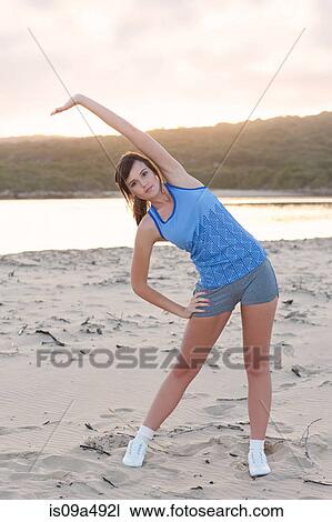 Stock Image - Runner stretching on beach. Fotosearch