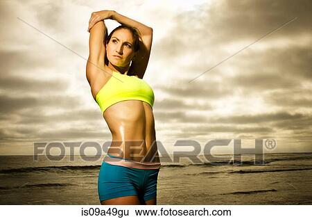 Stock Photograph - Runner stretching on beach. Fotosearch