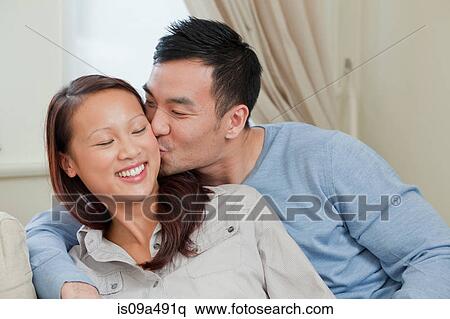 Smiling couple kissing on sofa View Large Photo Image Stock Photography - Smiling couple kissing on sofa. Fotosearch