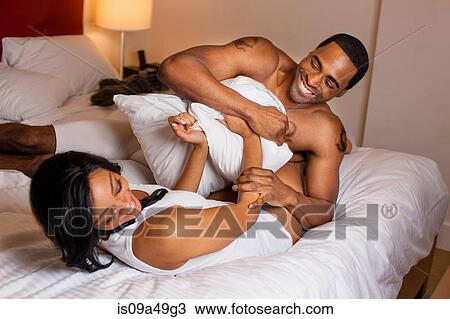 Stock Image - Smiling couple playing in bed. Fotosearch