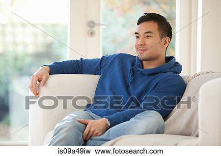 Smiling man relaxing on sofa View Large Photo Image Stock Photo - Smiling man relaxing on sofa. Fotosearch