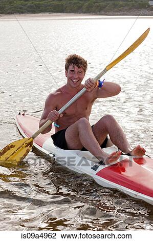 Stock Image - Smiling man rowing kayak in lake. Fotosearch