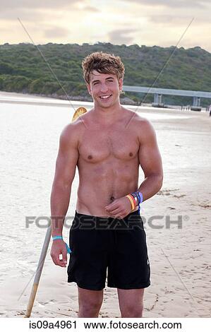 Stock Image - Smiling man standing on beach. Fotosearch