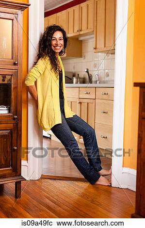 Stock Image - Smiling woman leaning in doorway. Fotosearch