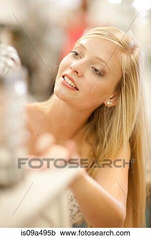 Stock Image - Smiling woman shopping in store. Fotosearch