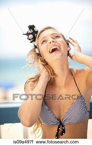 Stock Image - Smiling woman tying scarf in hair. Fotosearch