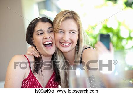 Stock Photography - Smiling women taking pictures together. Fotosearch