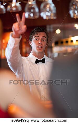 Waiter offering more drinks at bar View Large Photo Image Stock Photography - Waiter offering more drinks at bar. Fotosearch