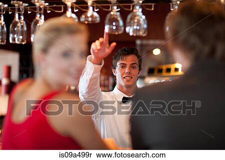 Stock Photography - Waiter offering more drinks at bar. Fotosearch
