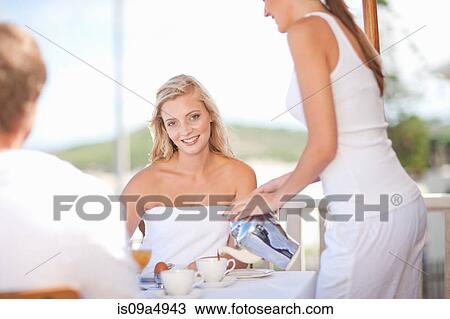 Stock Image - Waitress serving woman coffee at table. Fotosearch