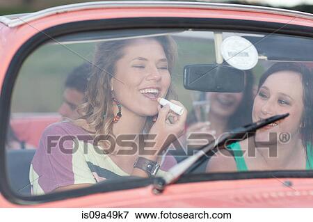 Stock Photo - Woman applying lipstick in convertible. Fotosearch