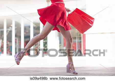 Stock Image - Woman carrying shopping bag outdoors. Fotosearch