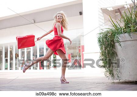 Stock Image - Woman carrying shopping bag outdoors. Fotosearch