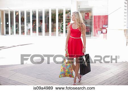 Stock Photo - Woman carrying shopping bags outdoors. Fotosearch