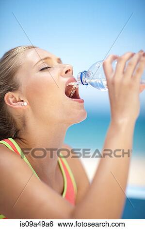 Stock Photograph - Woman drinking water bottle outdoors. Fotosearch
