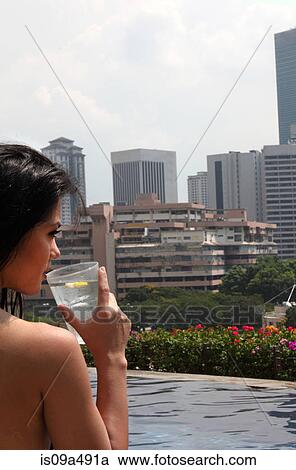 Stock Image - Woman drinking water by pool. Fotosearch