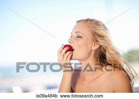 Stock Image - Woman eating apple outdoors. Fotosearch