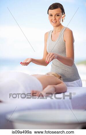 Stock Image - Woman giving massage on beach. Fotosearch