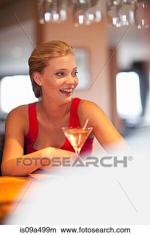 Picture - Woman having drink at bar. Fotosearch