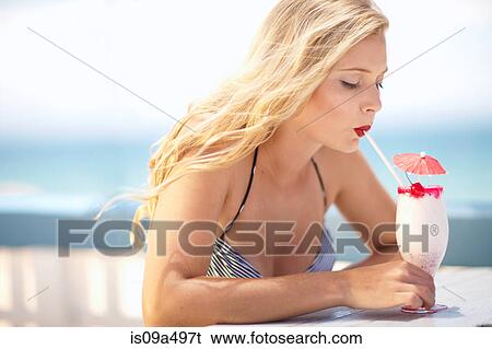 Stock Photograph - Woman having tropical drink outdoors. Fotosearch