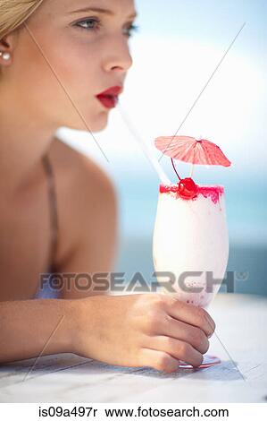 Stock Photography - Woman having tropical drink outdoors. Fotosearch