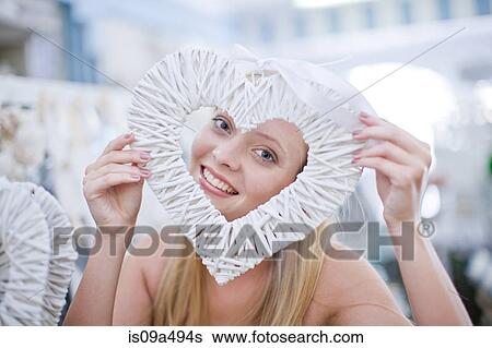 Stock Photograph - Woman holding heart shaped decoration. Fotosearch