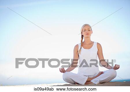 Stock Image - Woman meditating on beach. Fotosearch