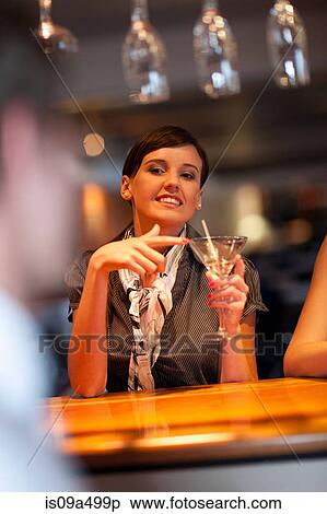 Stock Photography - Woman ordering another drink at bar. Fotosearch