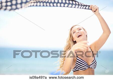 Stock Image - Woman playing with scarf on beach. Fotosearch