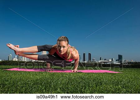 Stock Image - Woman practicing yoga in urban park. Fotosearch