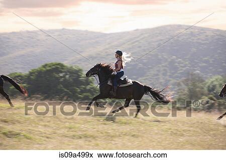 Stock Photo - Woman riding horse in rural landscape. Fotosearch