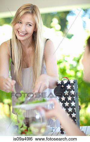 Stock Photograph - Woman serving salad at table. Fotosearch
