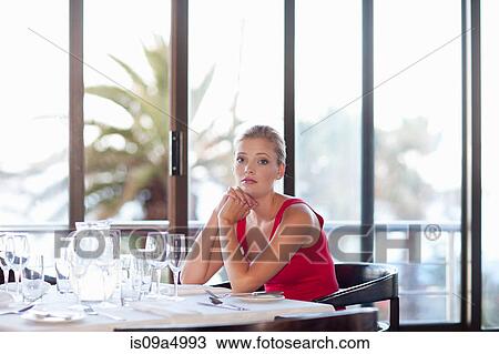 Woman sitting at restaurant table View Large Photo Image Stock Image - Woman sitting at restaurant table. Fotosearch
