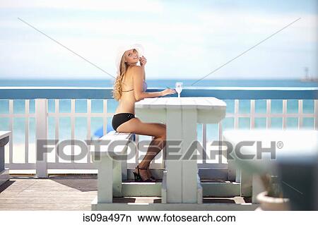 Picture - Woman sitting at table on deck. Fotosearch
